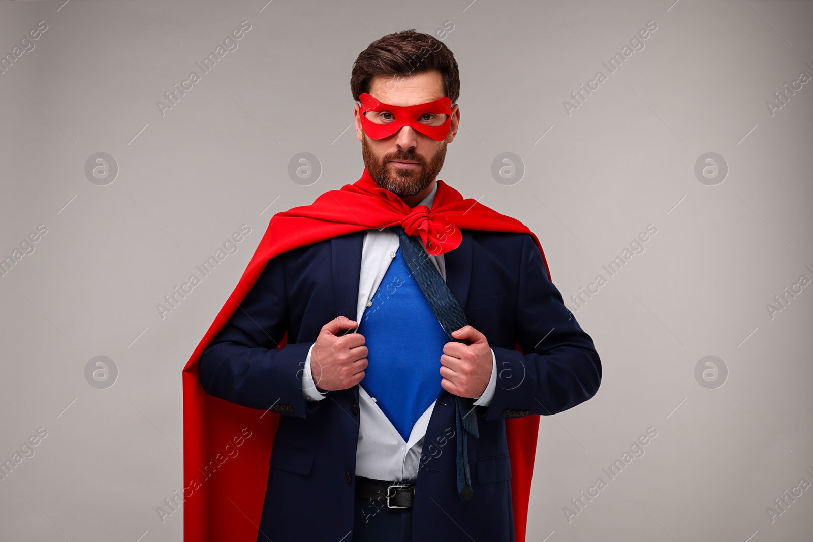 Photo of Confident businessman wearing superhero costume under suit on beige background