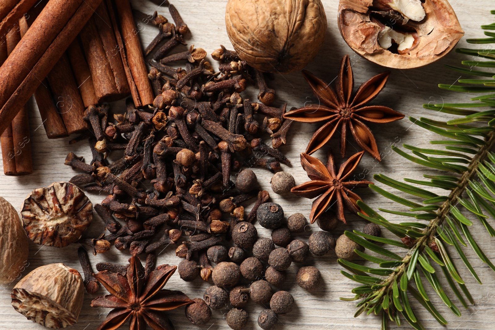 Photo of Different spices, nuts and fir branch on wooden table, flat lay