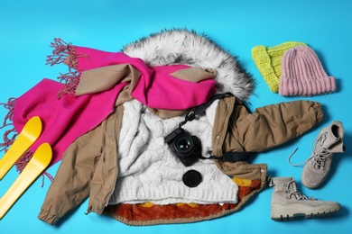 Flat lay composition with warm clothes for winter vacation on color background