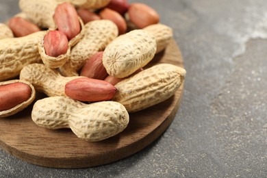 Photo of Fresh unpeeled peanuts on grey table, closeup. Space for text