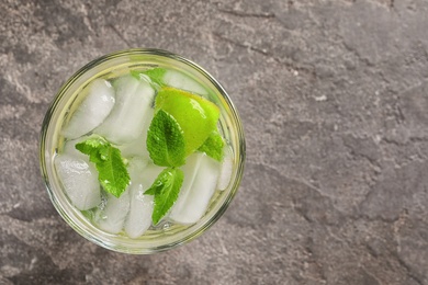 Refreshing beverage with mint and lime in glass on grey background, top view