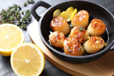 Photo of Delicious fried scallops and ingredients on dark gray textured table, closeup