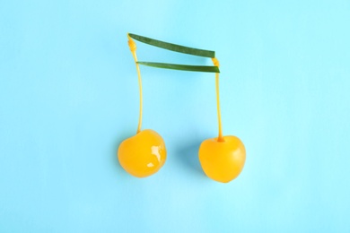 Photo of Musical note made of onion and cocktail cherries on color background, top view