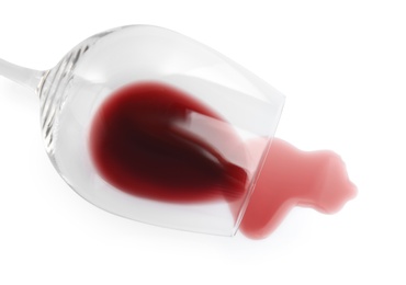 Photo of Transparent glass and spilled exquisite red wine on white background