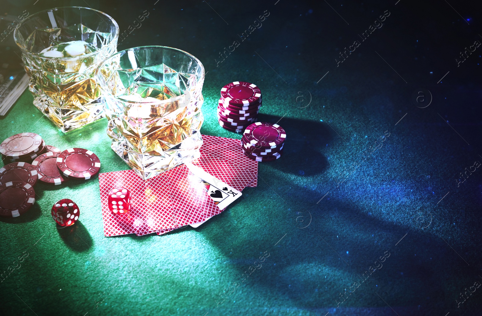 Image of Casino chips, dice, playing cards and glasses of whiskey on green table, space for text