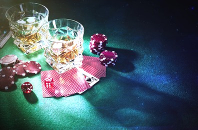Image of Casino chips, dice, playing cards and glasses of whiskey on green table, space for text