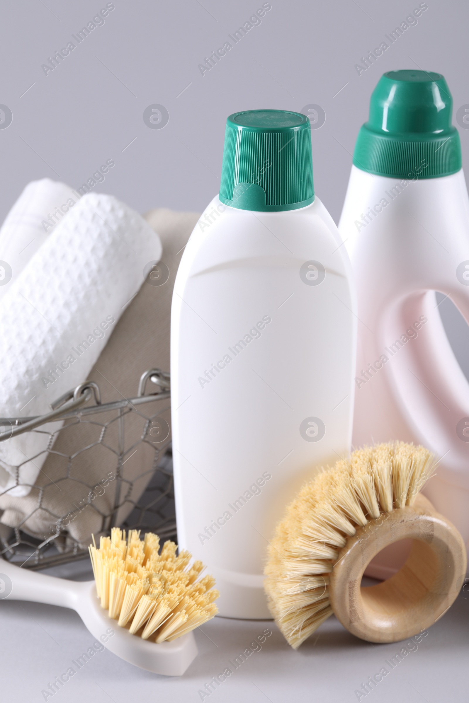 Photo of Bottles of cleaning product, brushes and rags on light background