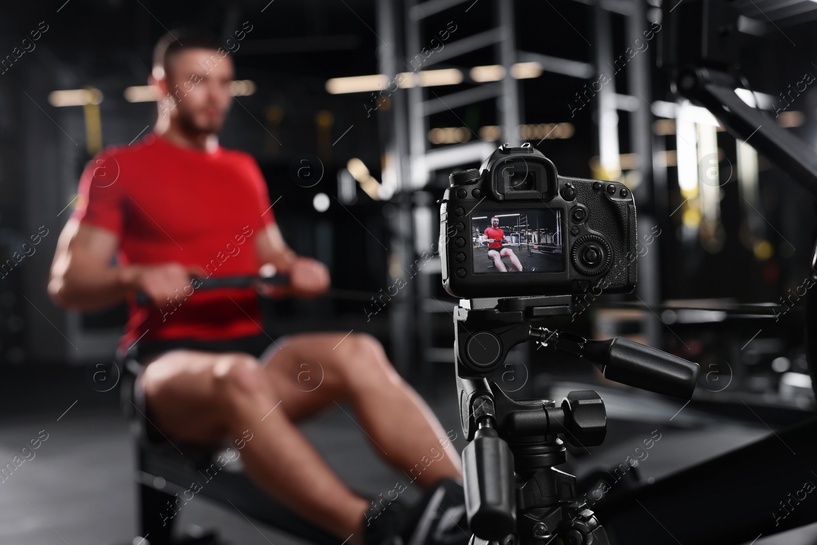 Photo of Man recording workout on camera at gym. Online fitness trainer