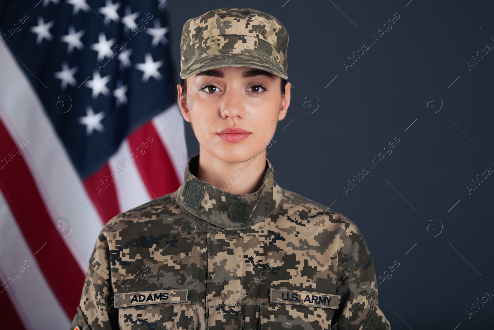 Photo of Female American soldier and flag of USA on dark background. Military service