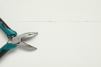 Bent nose pliers on white wooden table, top view. Space for text