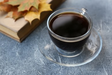 Photo of Glass cup with coffee and book on grey table, closeup. Morning ritual