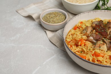 Photo of Delicious pilaf with meat and carrot on light grey table, closeup. Space for text