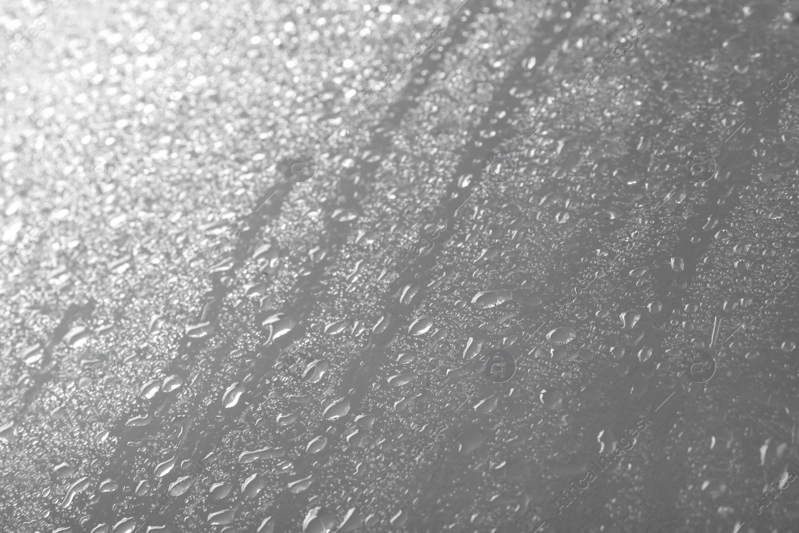 Photo of Glass with rain drops against light background