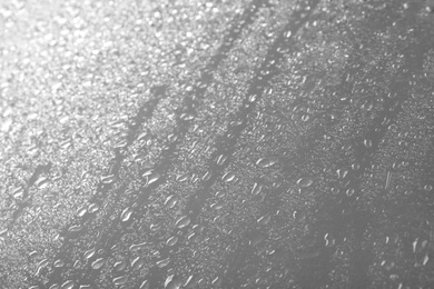 Photo of Glass with rain drops against light background