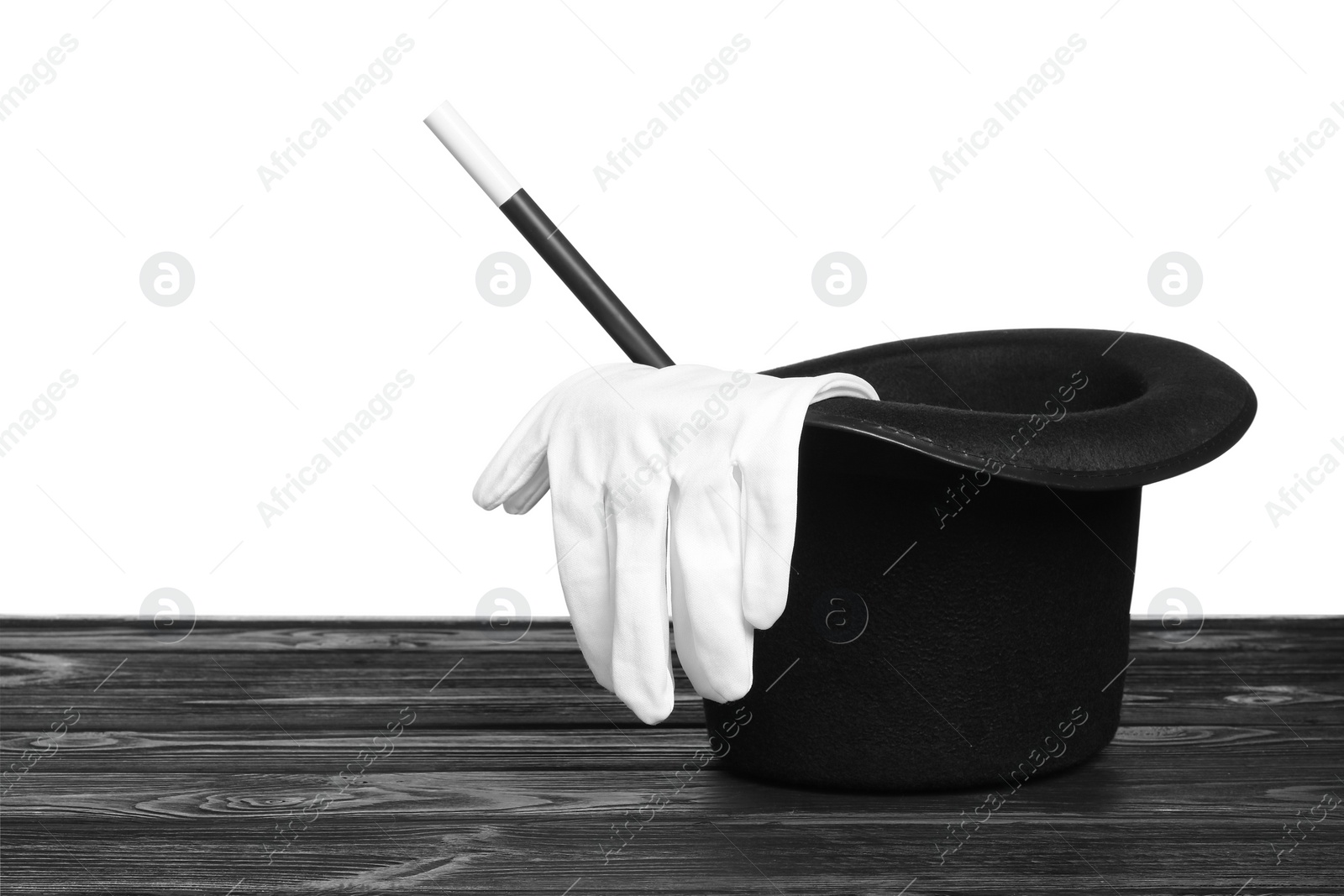 Photo of Magician's hat, gloves and wand on wooden table against white background