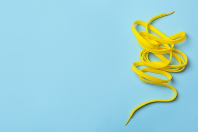 Yellow shoelace on light blue background, top view. Space for text