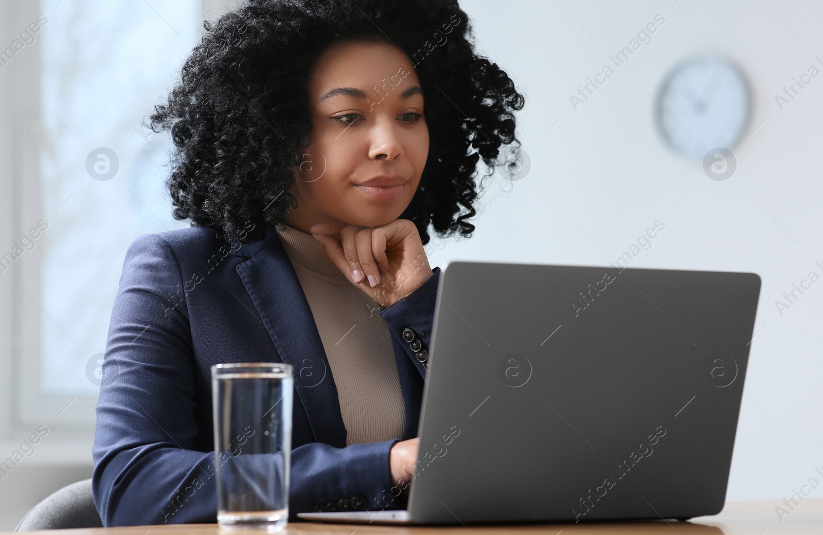 Photo of Young woman working on laptop at table in office