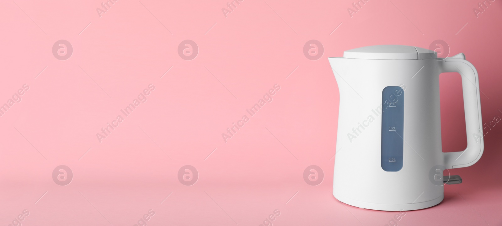Photo of New modern electric kettle on pink background, space for text