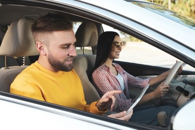 Young man using tablet and driver in modern car