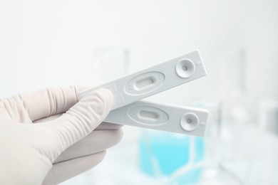 Photo of Doctor holding two disposable express tests for hepatitis indoors, closeup
