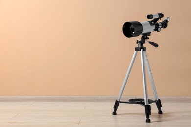 Photo of Tripod with modern telescope near beige wall. Space for text
