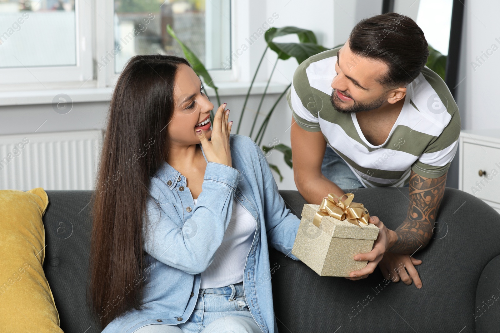 Photo of Man presenting gift to his girlfriend at home