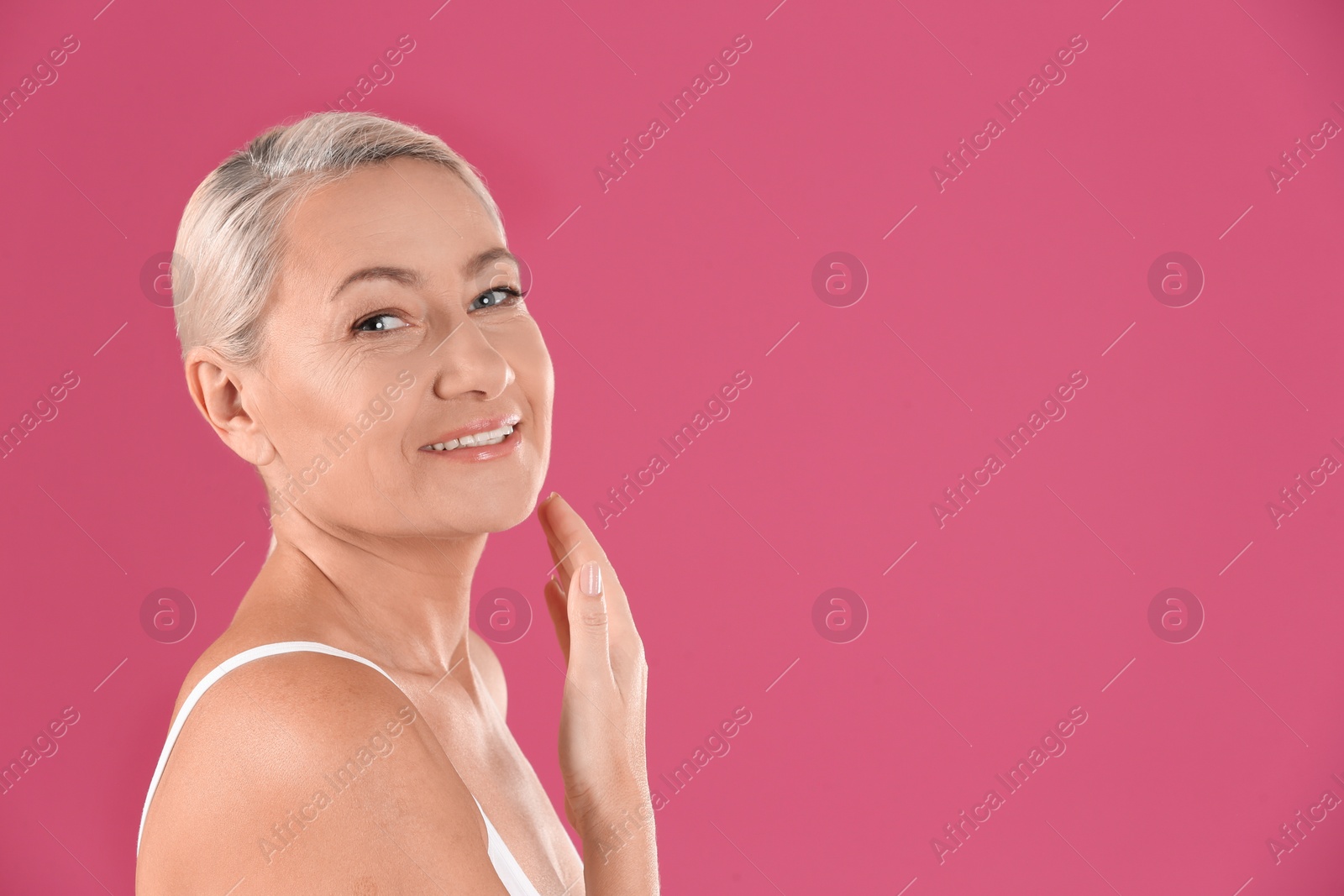 Photo of Portrait of beautiful mature woman on pink background. Space for text