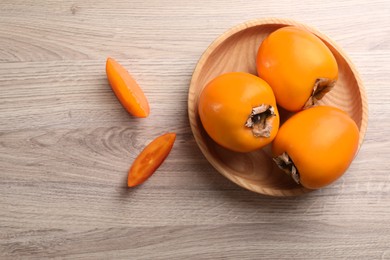 Photo of Delicious ripe persimmons on light wooden table, top view. Space for text