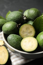 Photo of Fresh green feijoa fruits in bowl on black table, closeup