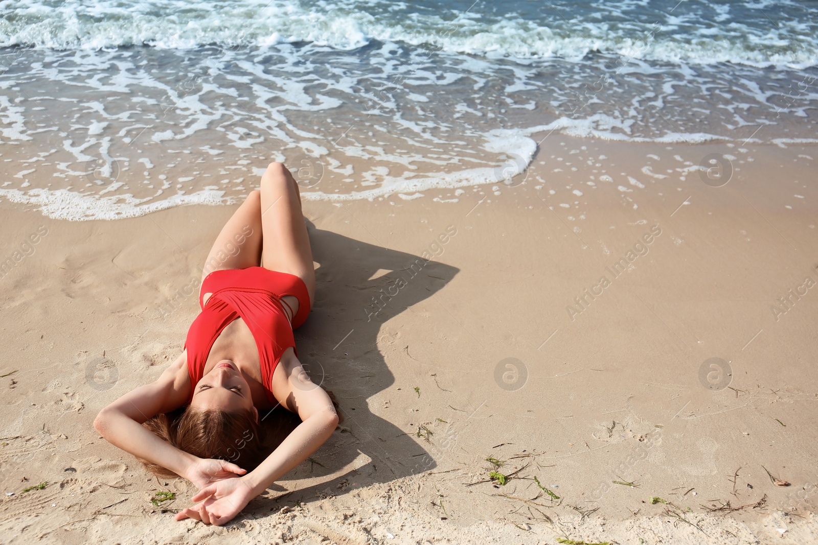 Photo of Attractive young woman in beautiful one-piece swimsuit on beach