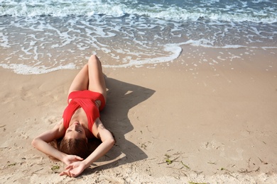 Photo of Attractive young woman in beautiful one-piece swimsuit on beach