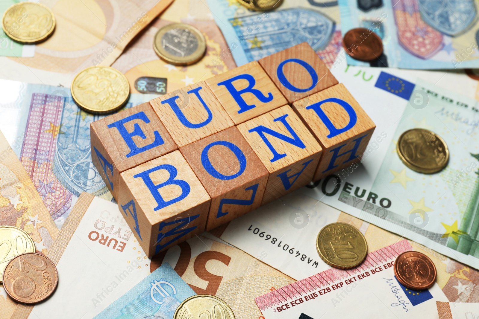 Photo of Wooden cubes with word Eurobond and coins on euro banknotes