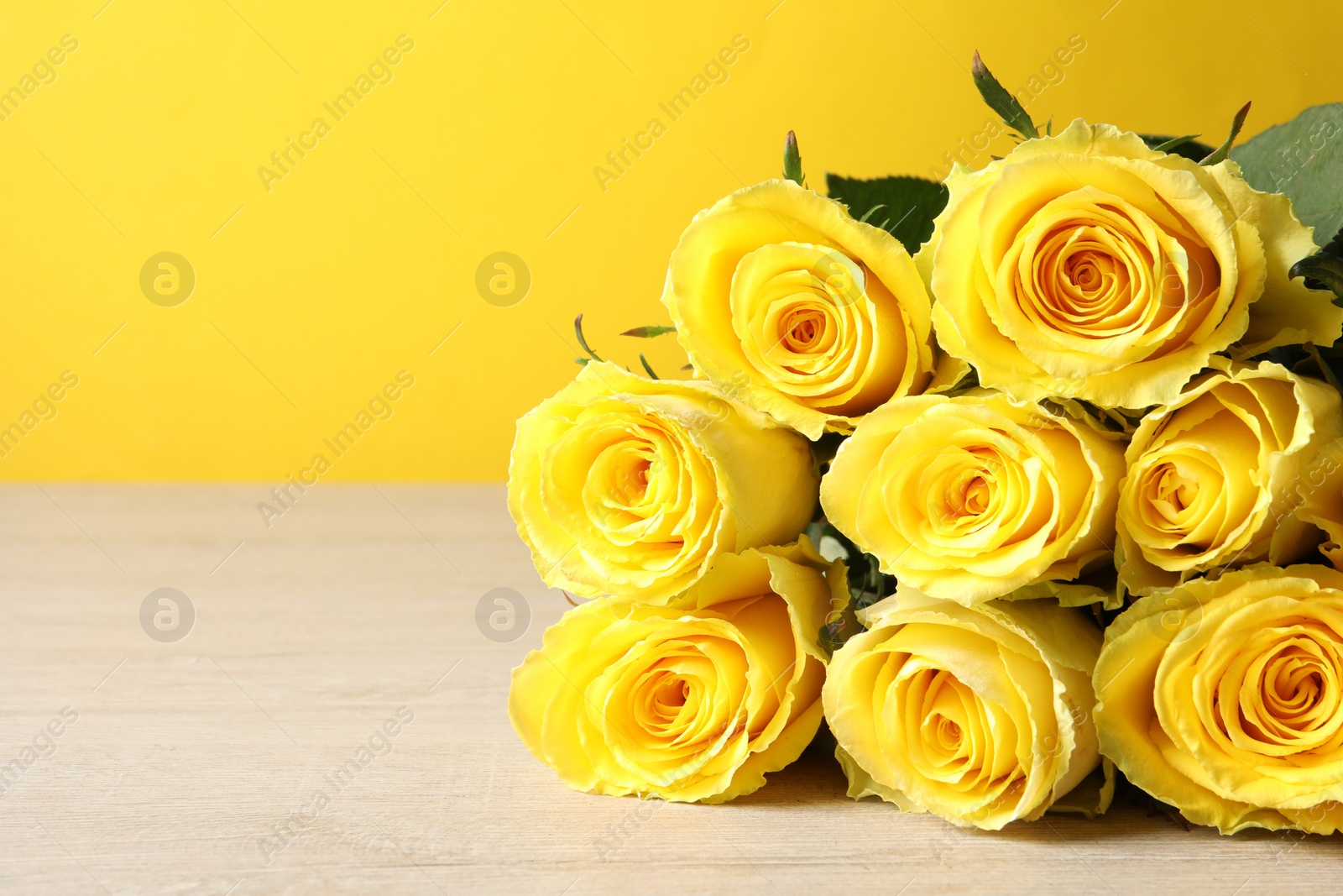 Photo of Beautiful bouquet of yellow roses on wooden table, closeup. Space for text