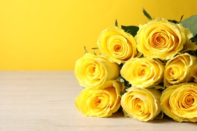 Beautiful bouquet of yellow roses on wooden table, closeup. Space for text