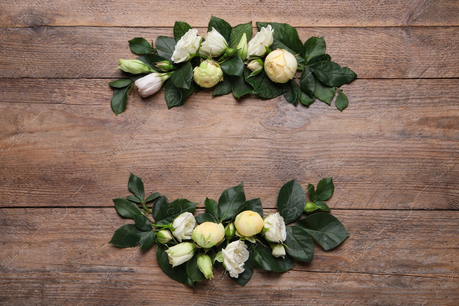 Photo of Wreath made of beautiful flowers and green leaves on wooden background, flat lay. Space for text