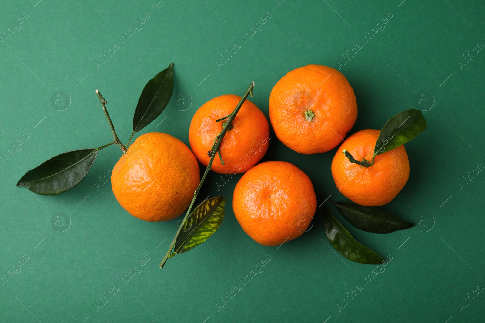 Photo of Fresh ripe tangerines with leaves on green background, flat lay