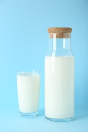 Photo of Carafe and glass of fresh milk on light blue background