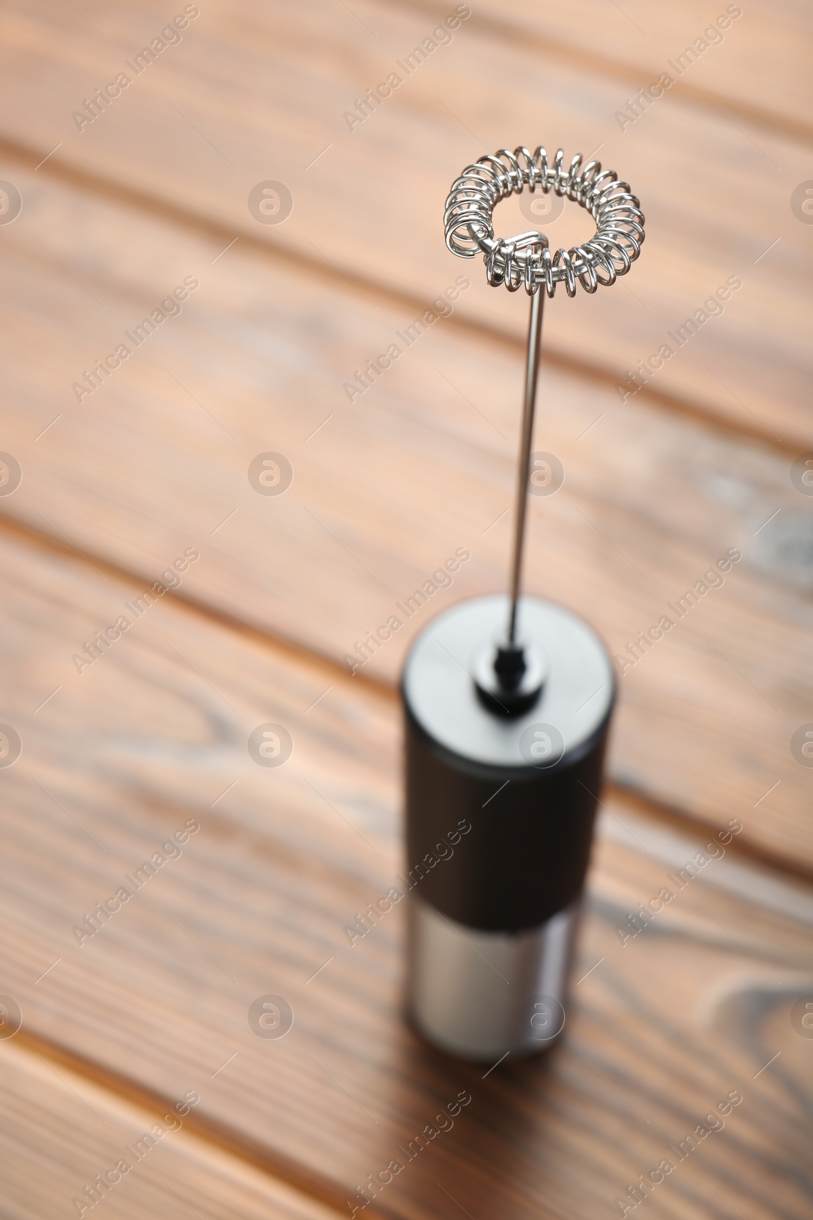 Photo of Black milk frother wand on wooden table