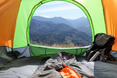 Photo of Camping tent with sleeping bag and backpack in mountains, view from inside