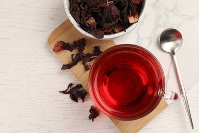 Photo of Cup of fresh hibiscus tea and dry flower leaves on wooden table, flat lay. Space for text
