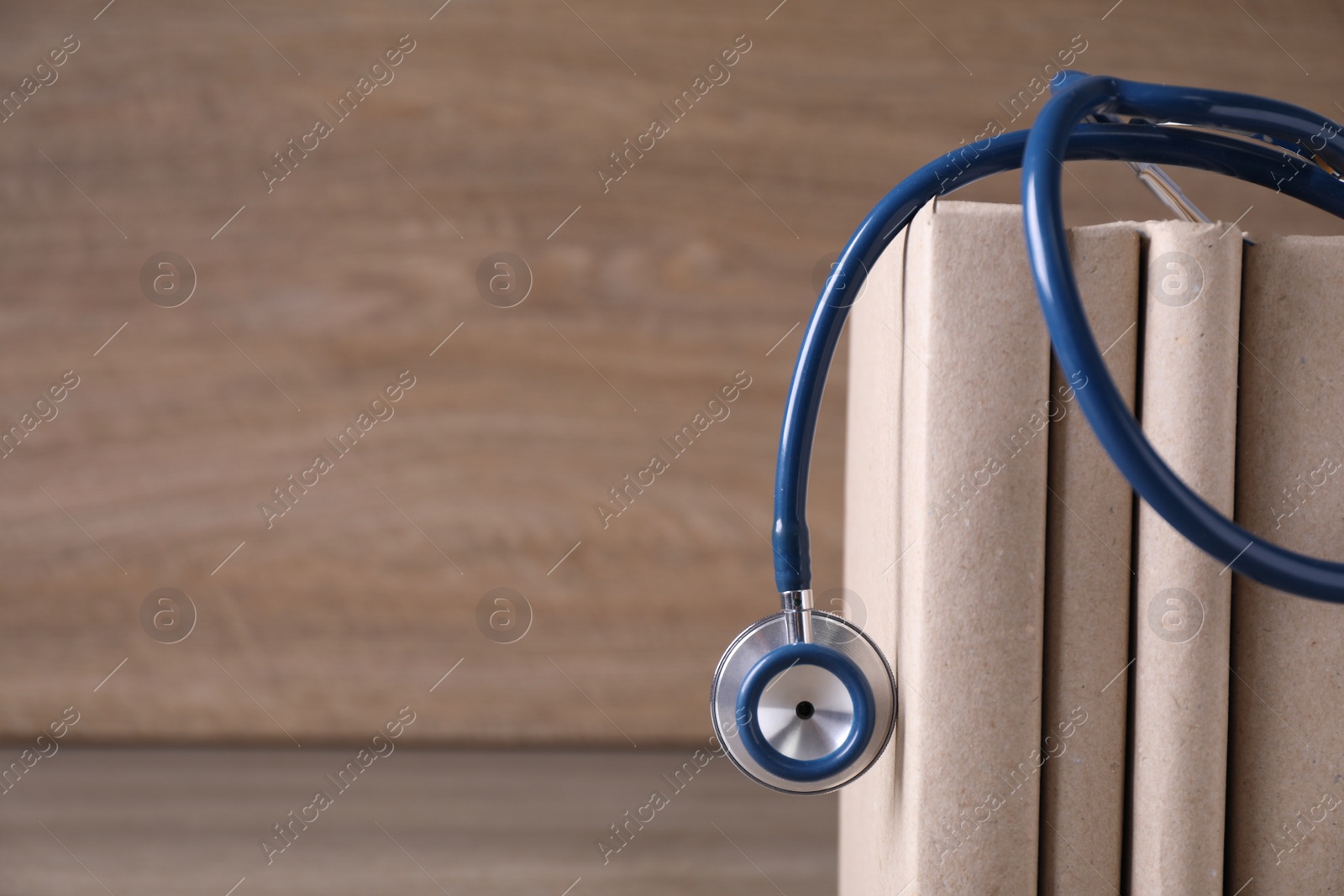 Photo of Closeup view of student textbooks and stethoscope on wooden table, space for text. Medical education