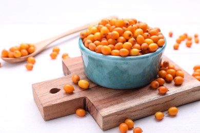 Bowl with fresh ripe sea buckthorn berries on white wooden table