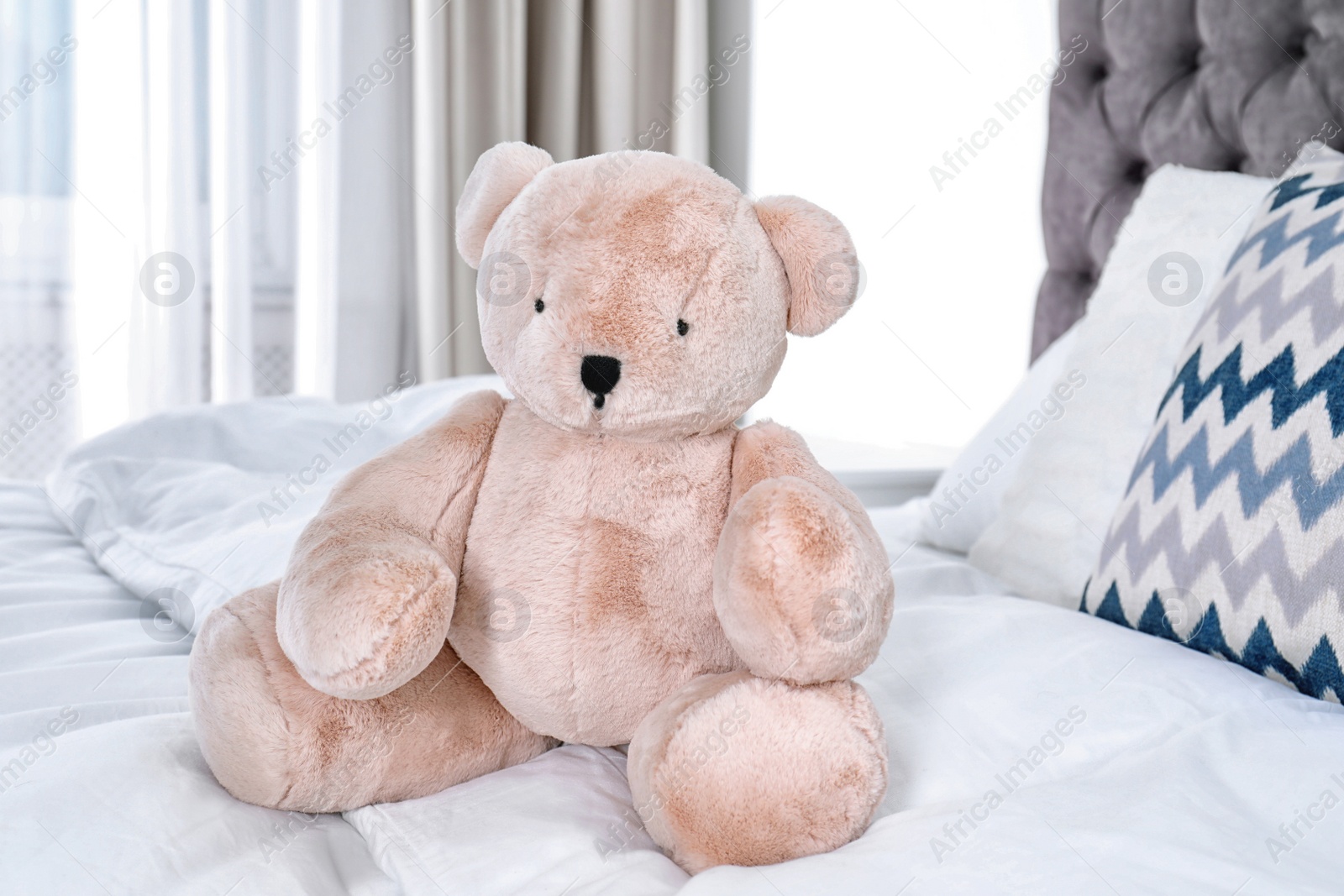 Photo of Cute teddy bear sitting on bed indoors