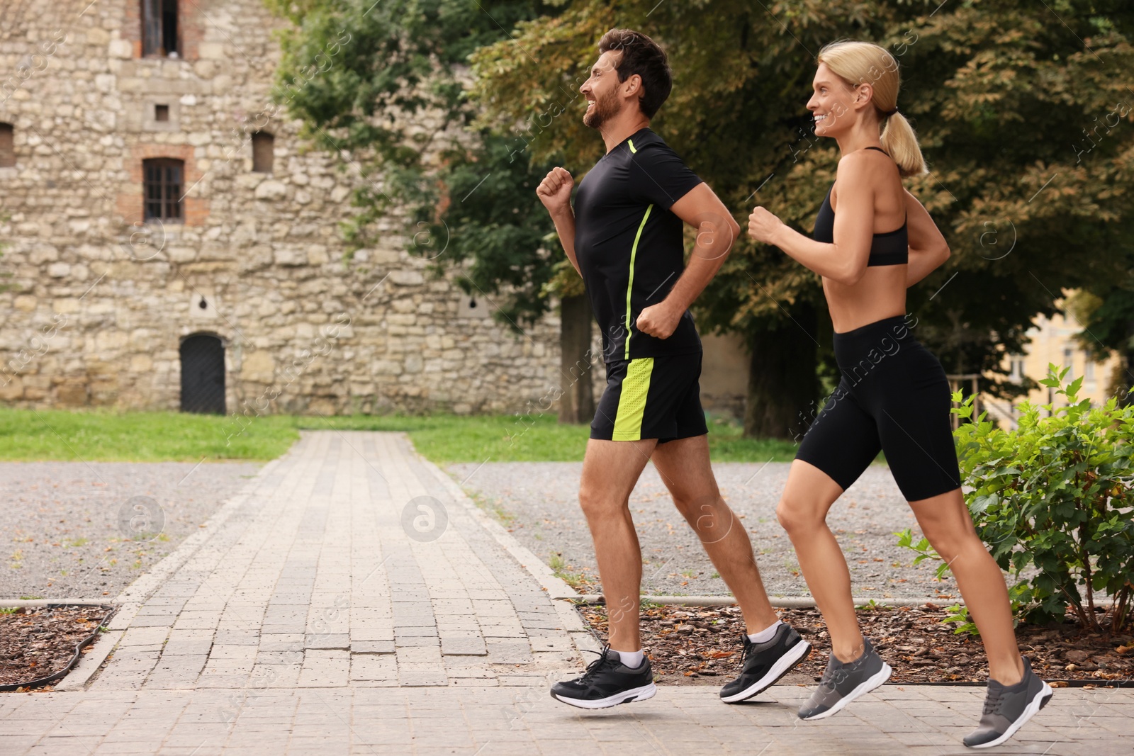 Photo of Healthy lifestyle. Happy couple running in park, space for text