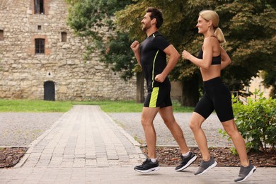 Healthy lifestyle. Happy couple running in park, space for text