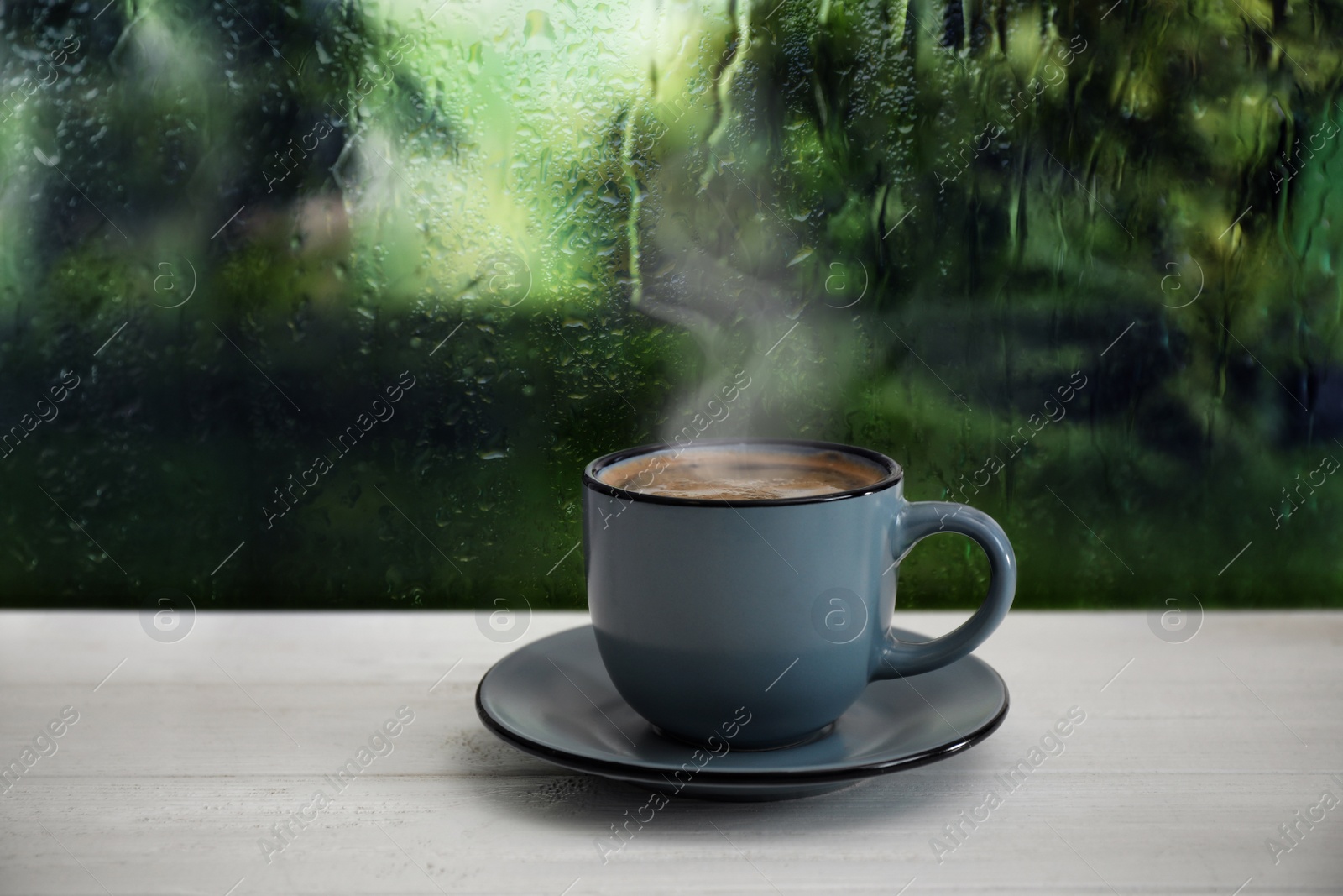 Image of Cup of hot drink near window on rainy day