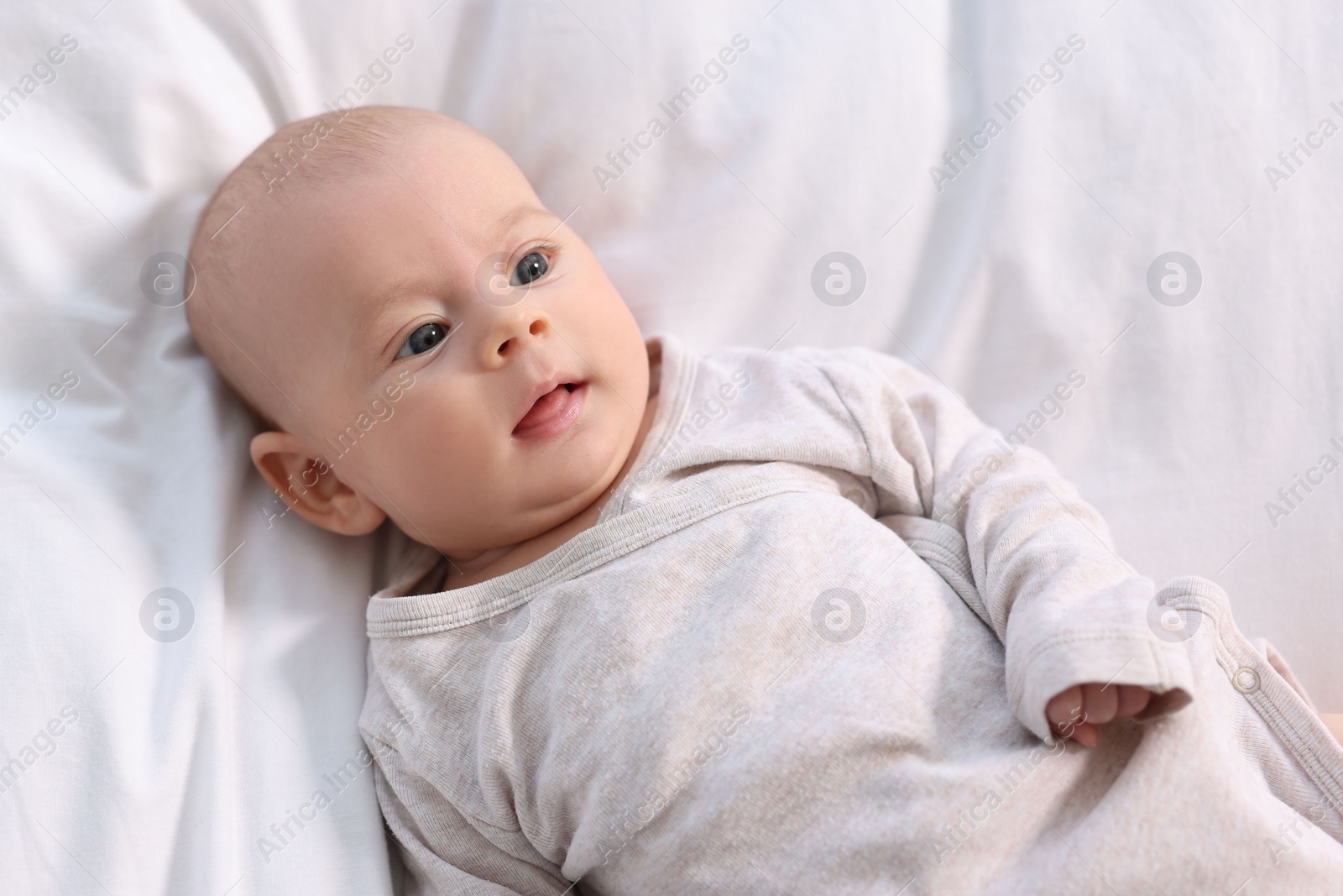 Photo of Cute little baby lying on white sheets