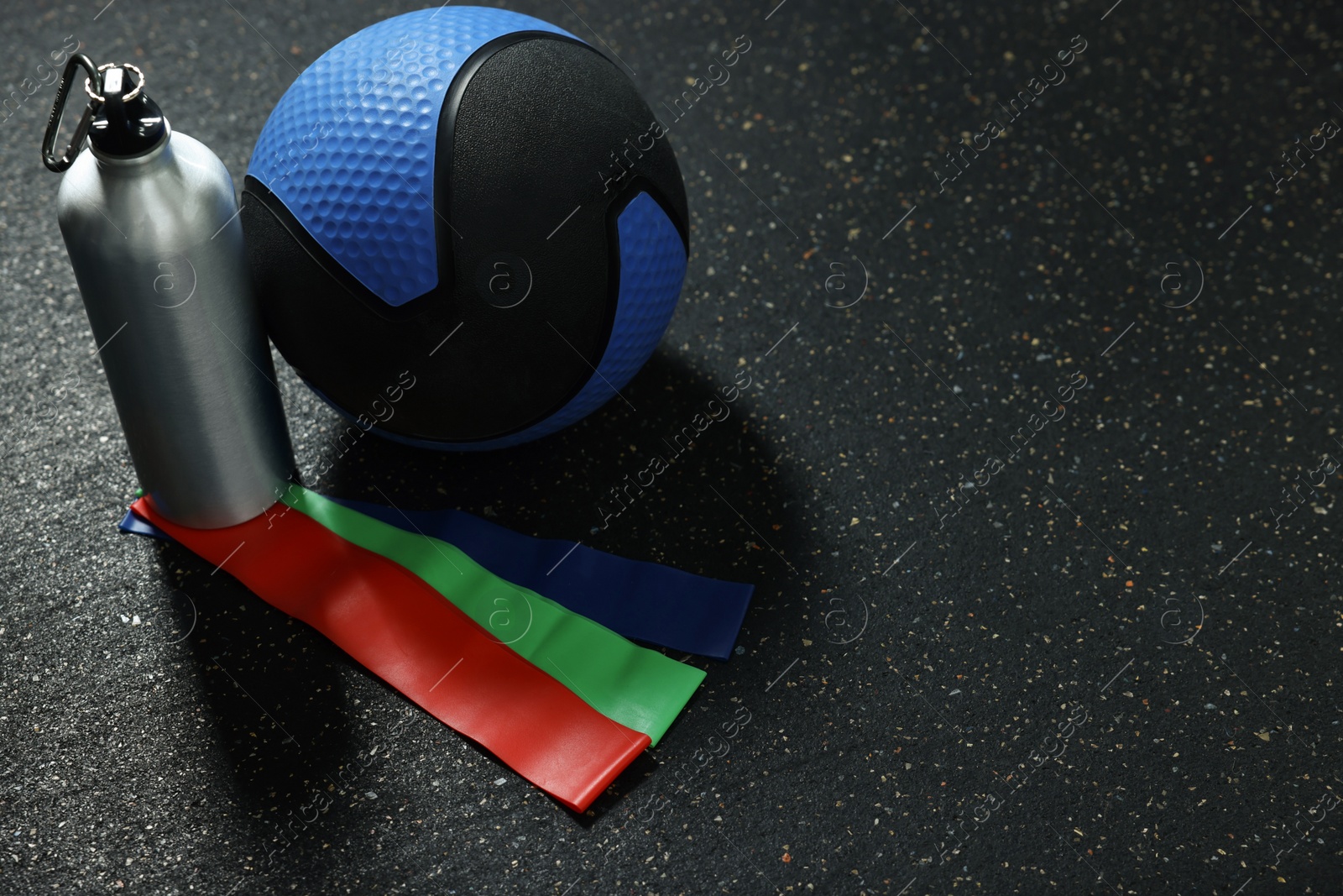 Photo of Blue medicine ball, bottle and elastic bands on floor, space for text