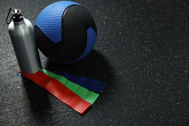 Photo of Blue medicine ball, bottle and elastic bands on floor, space for text