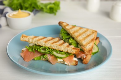 Photo of Blue plate with tasty sandwiches on white table
